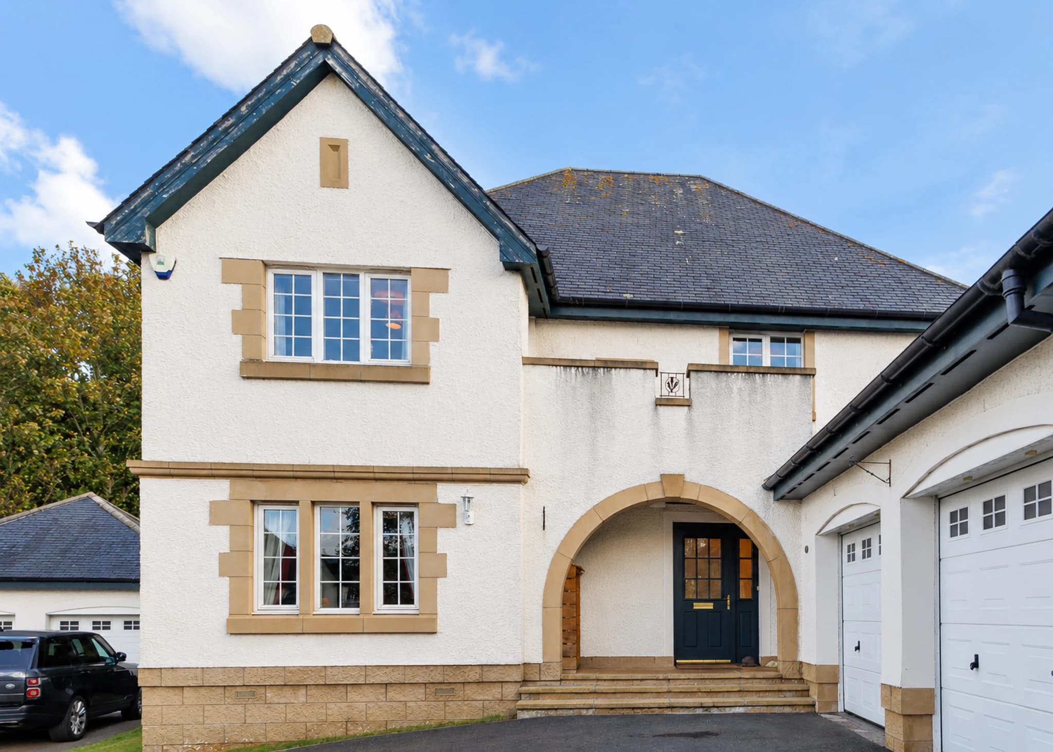Front exterior of 10 Burnet Crescent, showing its pale facade, arched entrance and adjoining garage