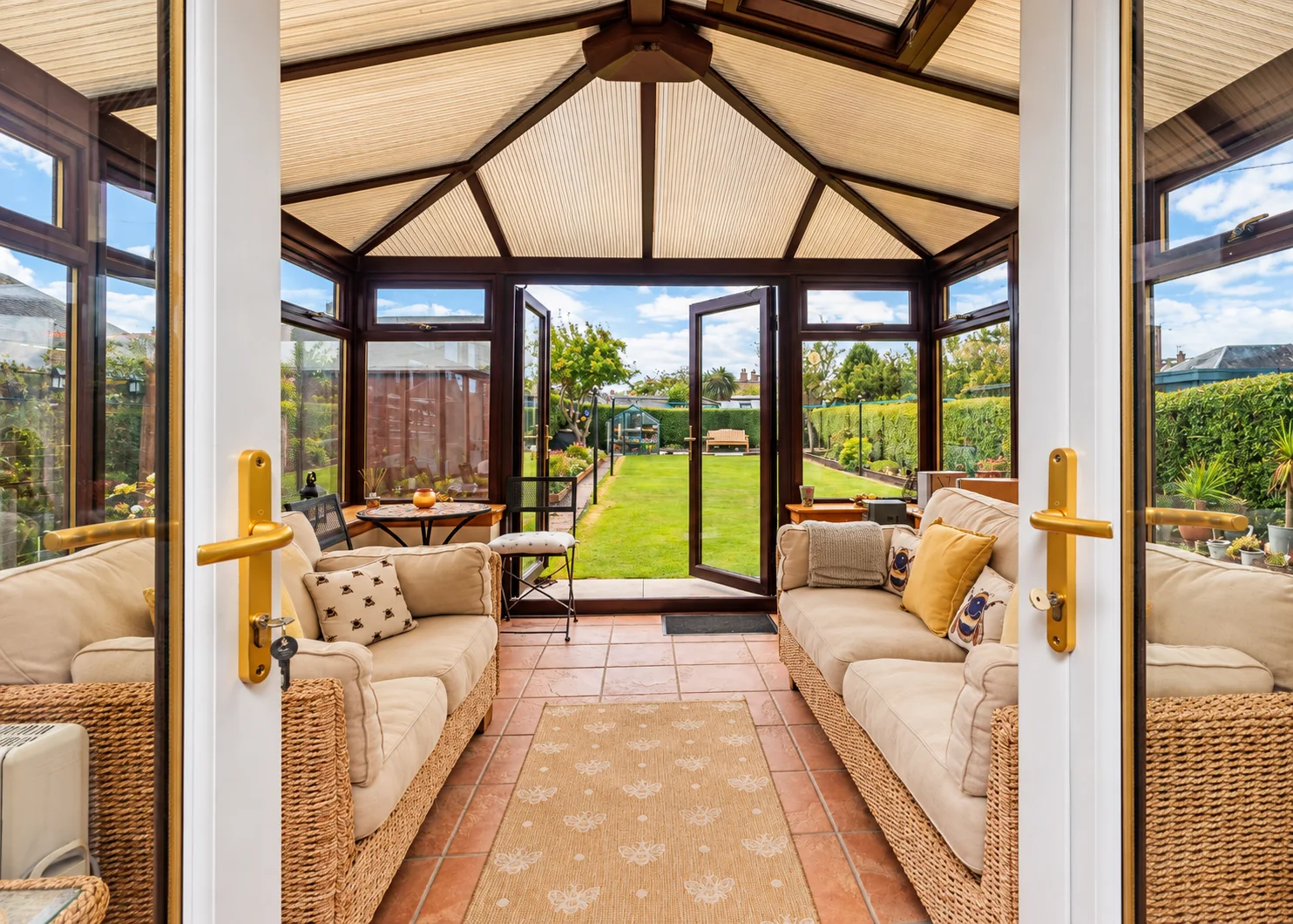 Open doors framing a conservatory, its roof structure and the garden beyond