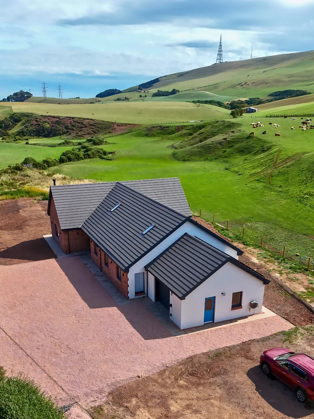 New-build home seen from above with open fields and hills beyond
